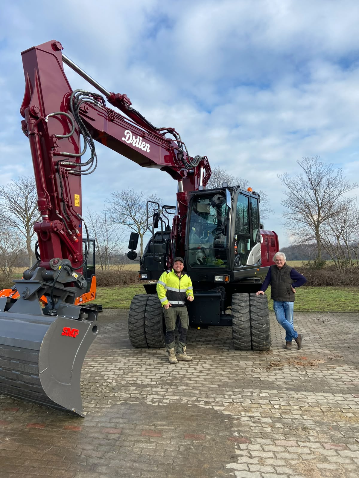 Zwei Mitarbeiter von Dieter Drüen vor einem Kettenbagger auf einer Baustelle